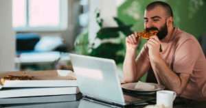 Man eating pizza at his laptop