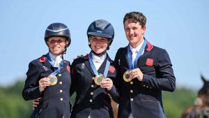 Ros Canter, Laura Collett and Tom McEwen stand on the Paris Olympics podium with their team gold medals