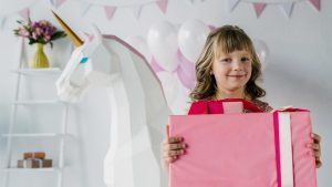 Girl receiving horsey Christmas gift with unicorn in background