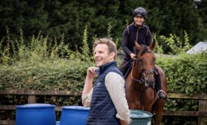 Billy Aprahamian laughing as he looks out of shot to the left, with his head girl Cara Spencer in the background on board Stone’s Throw.