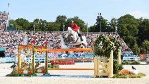 Christian Kukuk clears a oxer of orange poles iun front of the Paris Olympic crowds.