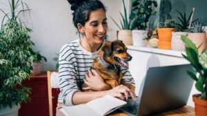 Woman working on laptop with dog on her lap