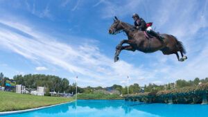 Showjumper Mark Edwards flies over a water jump at hickstead on Tinkers Tale