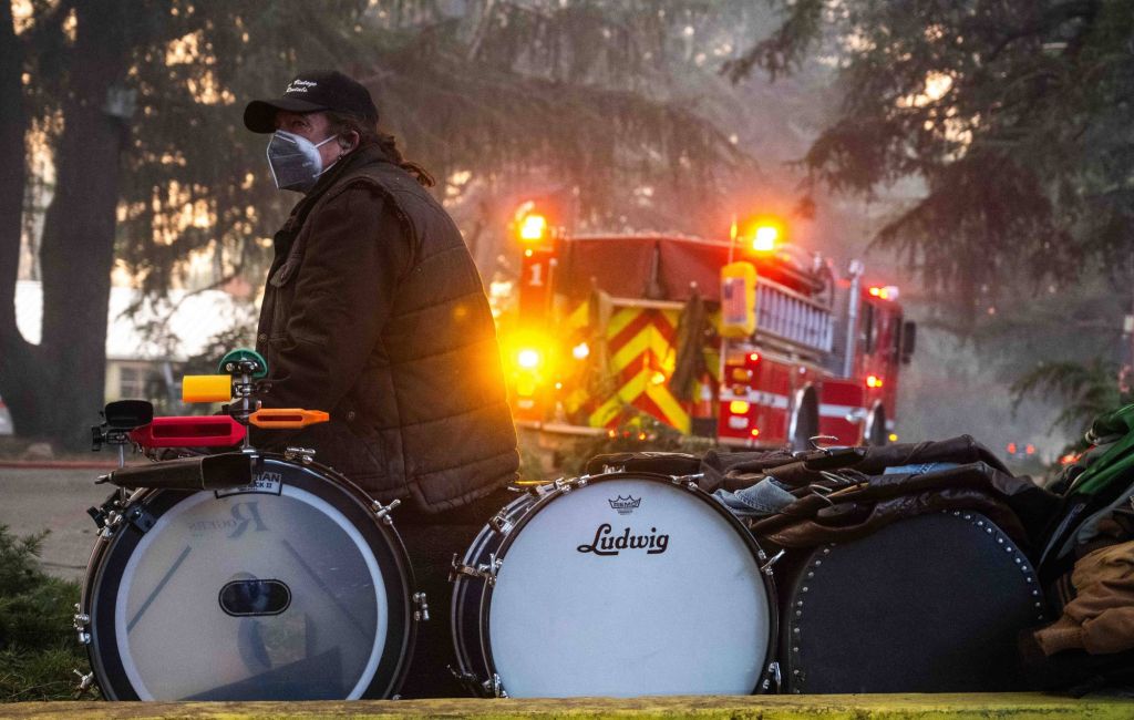 A man watches his home burn while sitting with a drum set and other belongings on Santa Rosa Avenue in Altadena on Wednesday, January 8, 2025 (Photo by Sarah Reingewirtz/MediaNews Group/Los Angeles Daily News via Getty Images)