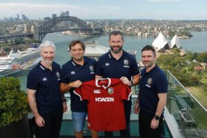 Aled Walters, David Nucifora, Andy Farrell and Vinny Hammond pose with a British & Irish Lions shirt in front of Sydney Harbour