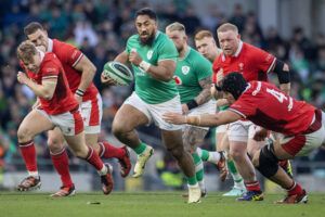 Ireland’s Bundee Aki runs with the ball as Welsh players try to make a tackle in the 2024 Six Nations