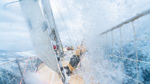 A man is falling on a yacht in choppy seas. The spray splashes around the close-up.