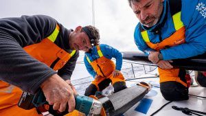 Jack Bouttell grinding away at a crack at the root of the starboard rudder of 11th Hour Racing Team during the 2022/23 The Ocean Race with crewmates Simon Fisher and Justine Mettraux.