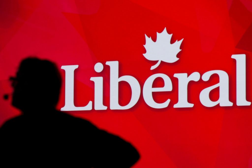 A man is silhouetted against a bright red background with Liberal spelled out in white