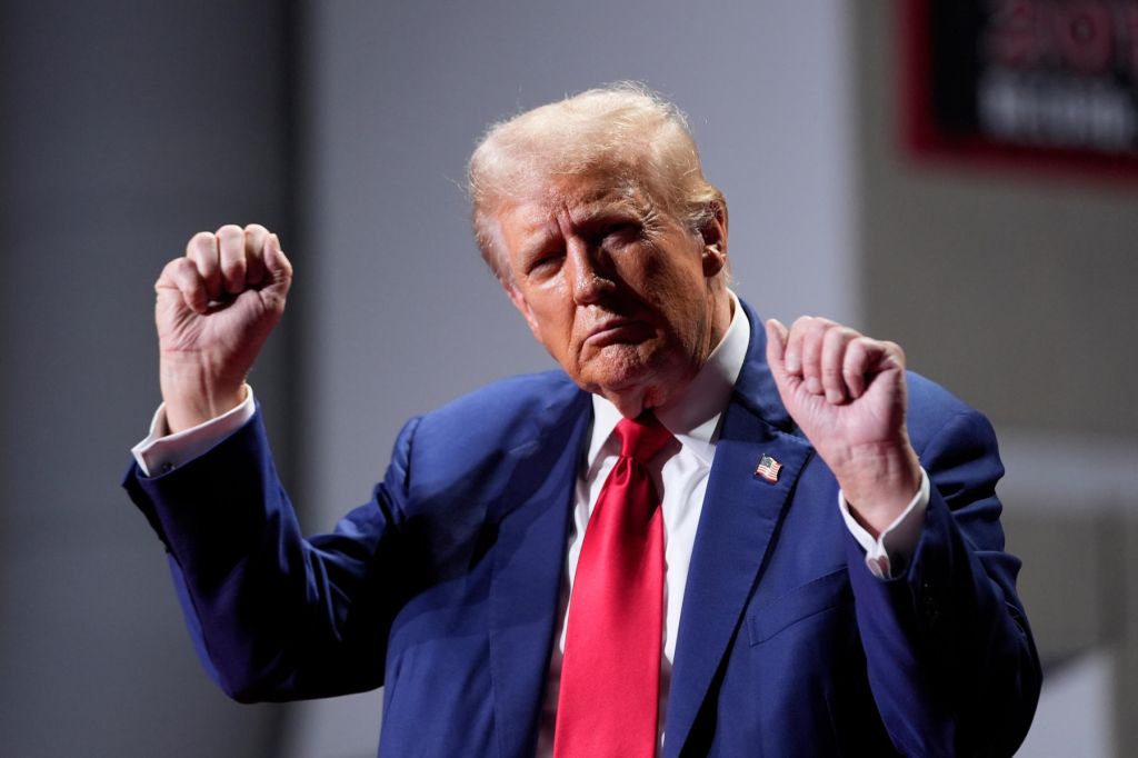 Trump, wearing a red tie and blue suit, clenches his hands while dancing