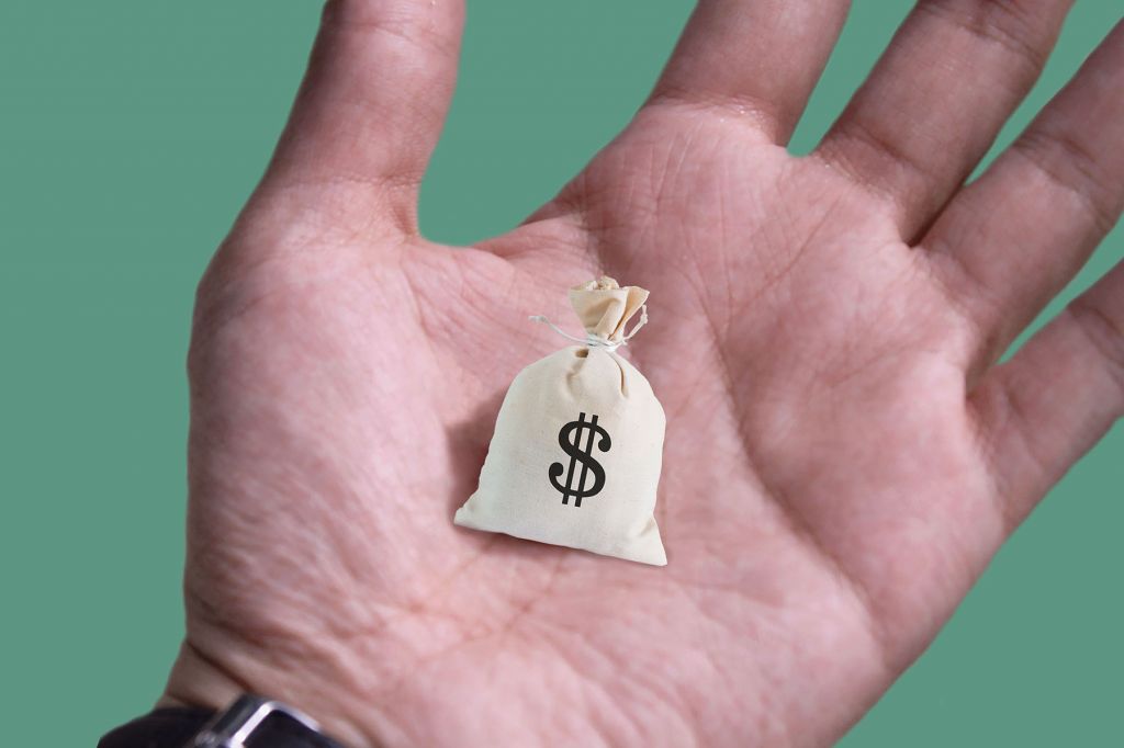 In a photo illustration, a hand holds a tiny sack of money