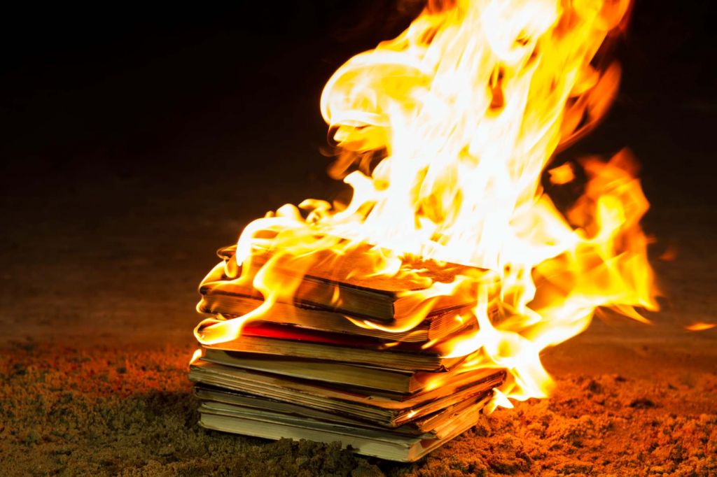 A few books are on fire against a black backdrop.