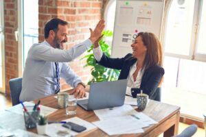 Two people in business attire give each other a high five.