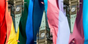 An image of Parliament Hill with a rainbow flag background.