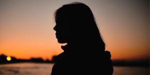 The silhouette of a woman as the sun sets in the background.