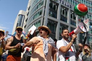 Members of the Palestinian solidarity contingent rally people at the end of the Pride march at Bank Street and Slater. A watermelon balloon hovers in the background.