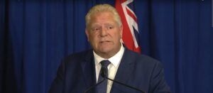 Doug Ford stands in front of a podium at a press conference.