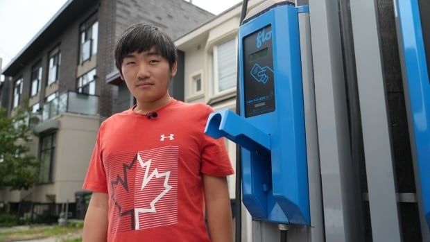 Man standing beside on-street EV charging station.