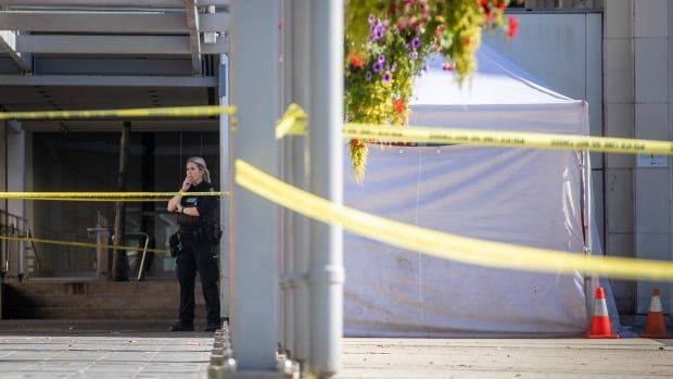 A VPD officer standing next to a white tent and crime scene tape