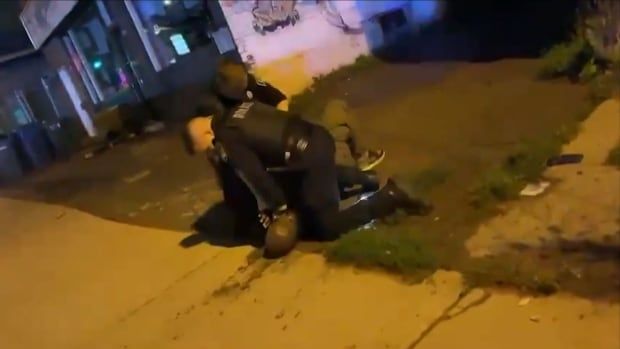 two police officers kneeling on a Black man.