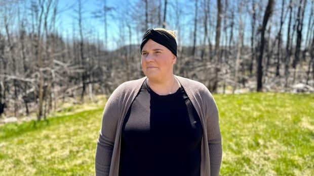 A person stands in front of burnt trees.