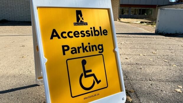 A yellow sadnwich board sign with a wheelchair symbol and the words 'Accessible Parking.'