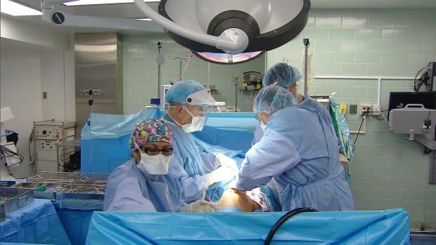 Four healthcare workers are seen in an operating room.