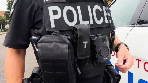 A police officer has a small camera mounted on the front of his uniform. 