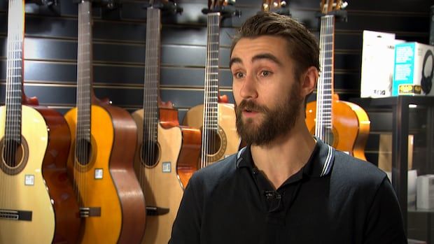 a man stands in front of guitars