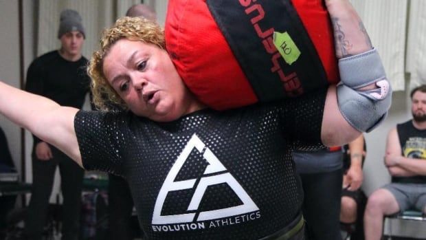 A woman carrying a large sandbag on her shoulder.