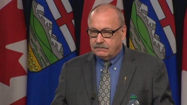 A man with glasses speaks at a podium.