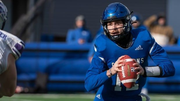 A man wearing all blue and a blue helmet carries a football