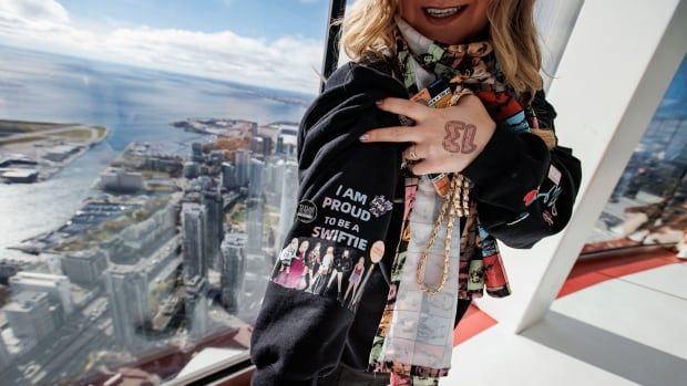 Taylor Swift fan shows off black sweatshirt, adorned with the words 'I am proud to be a Swiftie' and images of the mega star's different looks on her sleeve.