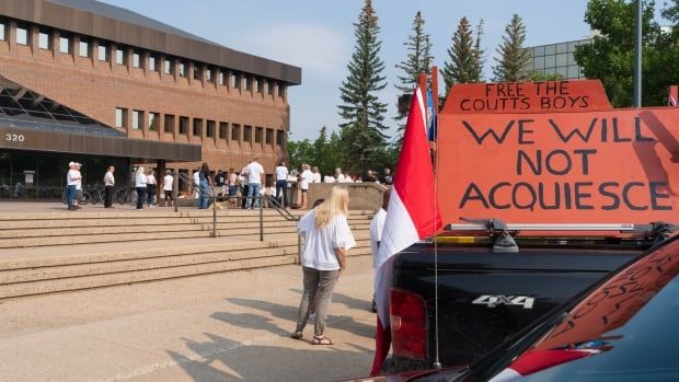 A red sign on a truck reads, "Free the Coutts boys. We will not acquiesce." 