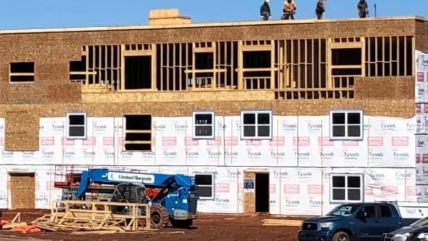 A housing construction project with workmen standing on roof.