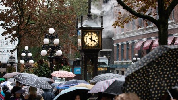 Tourists walk with umbrellas past the Gastown steam clock.