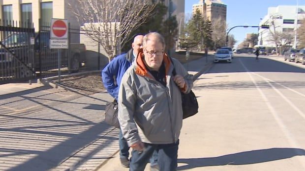 Man in grey coat leaves court house. 