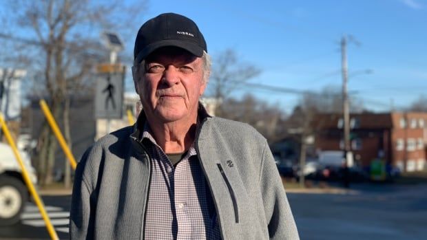 A man in a black baseball cap stands outside.