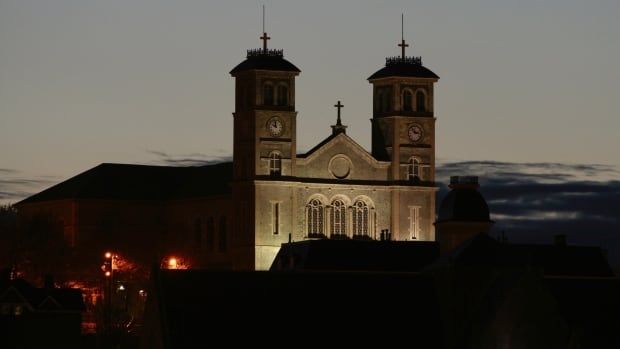 A night time view of a church towering above a darkened city skyline.