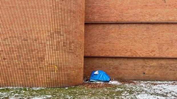 one blue tent on snowy grass outside a large brick building