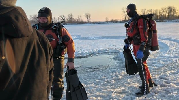 A rescue diver stands on a frozen pond.