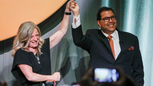 Notley and Nenshi hold their hands in the air.