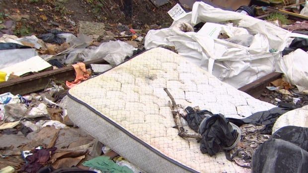 A large white mattress and other garbage lying on the ground.