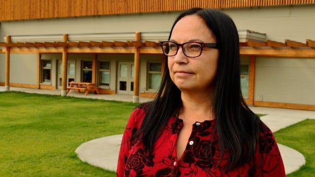 An Indigenous woman wearing red looks to her right.