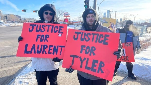 Two protesters hold signs saying "Justice for Tyler" and "Justice for Laurent."