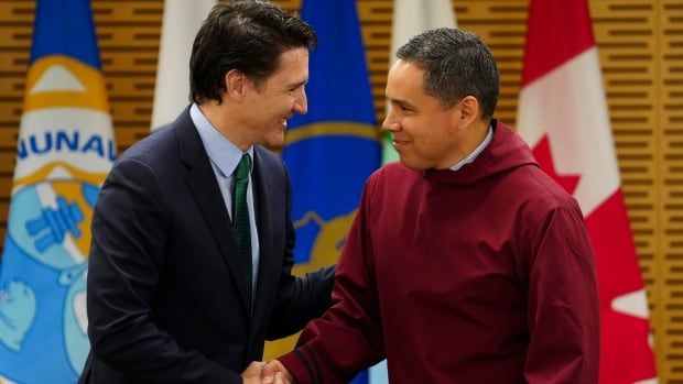 Two politicians shake hands during a meeting.