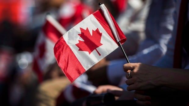 Hand holds Canadian flag.