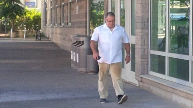 Man in white shirt walks down sidewalk