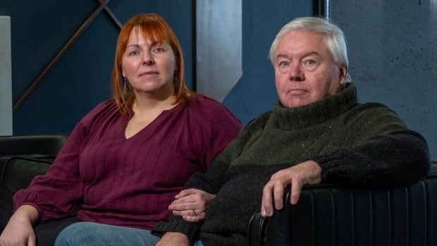 A woman and her father sit next to each other on a couch.