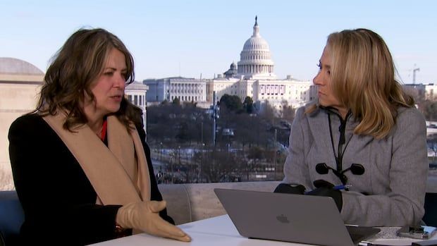 Two women talk at a table outside. 